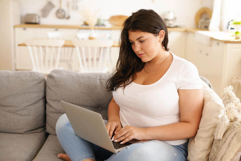 overweight woman on laptop on sofa